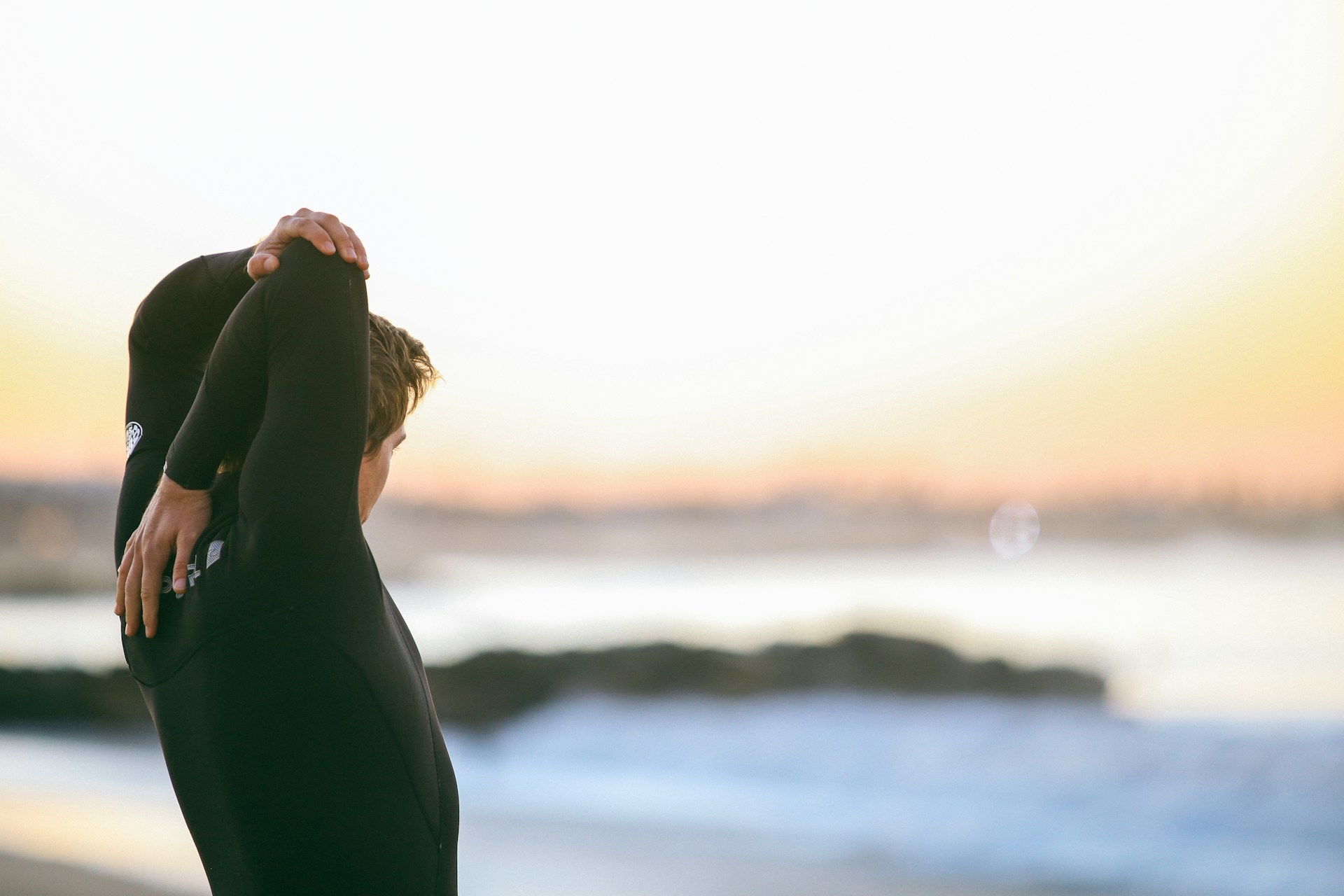Surfer in wetsuit stretching